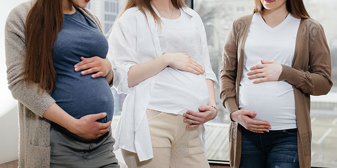 three pregnant women standing side by side